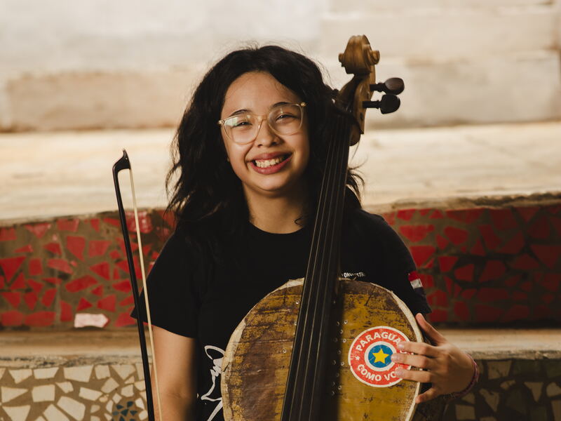 Ayelen lacht mit ihrem Cello aus einem Ölfass
