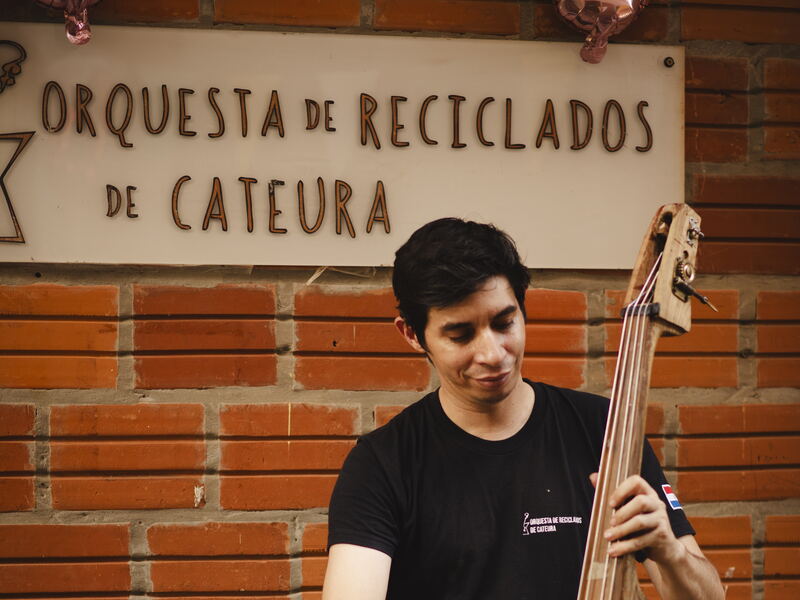 Wilson López spielt Kontrabass unter dem Schild der Orquesta de Reciclados de Cateura